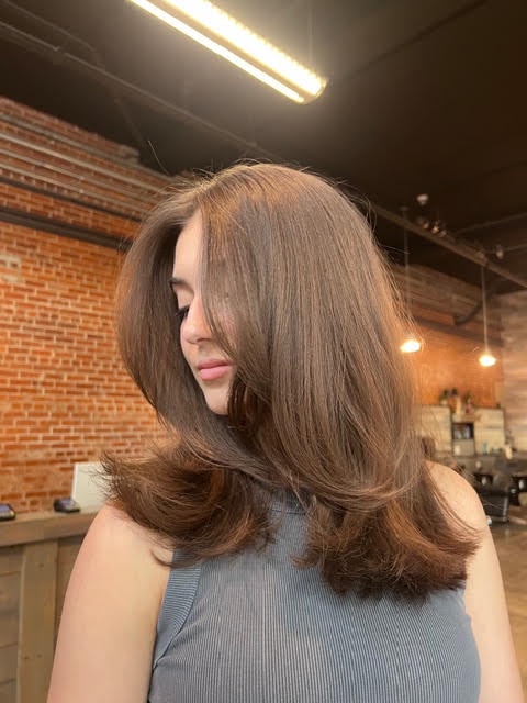 Woman with long layered brown hair styled in the salon